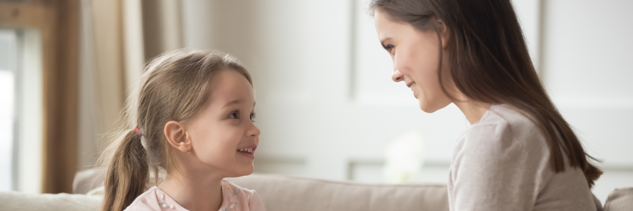 How I'm Encouraging My Daughter to Accept Her Autism Loving mother and child holding hands sitting on sofa.