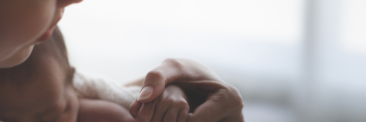 Raising Awareness to Help Support Mothers With Postpartum Depression Close up Mother holding hands with baby