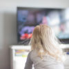 Young girl with blonde hair watching TV