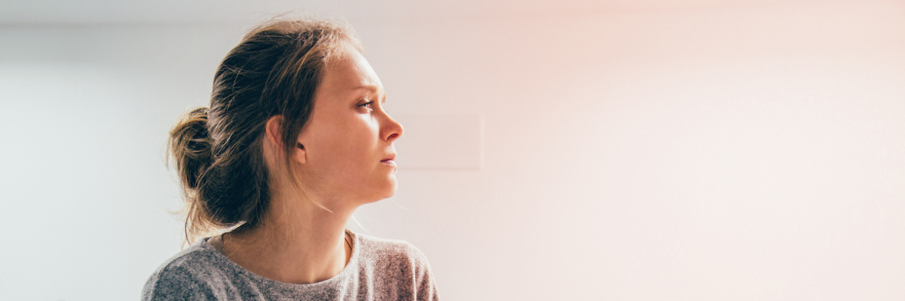 When I Realized Nausea Was Related to My Anxiety Woman with hands on stomach, looking aside