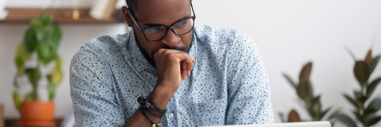 How to Support Men After Miscarriage photo of man sitting in front of laptop looking serious or concerned