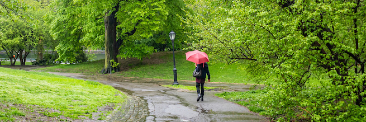 Woman walking on a path holding a red umbrella