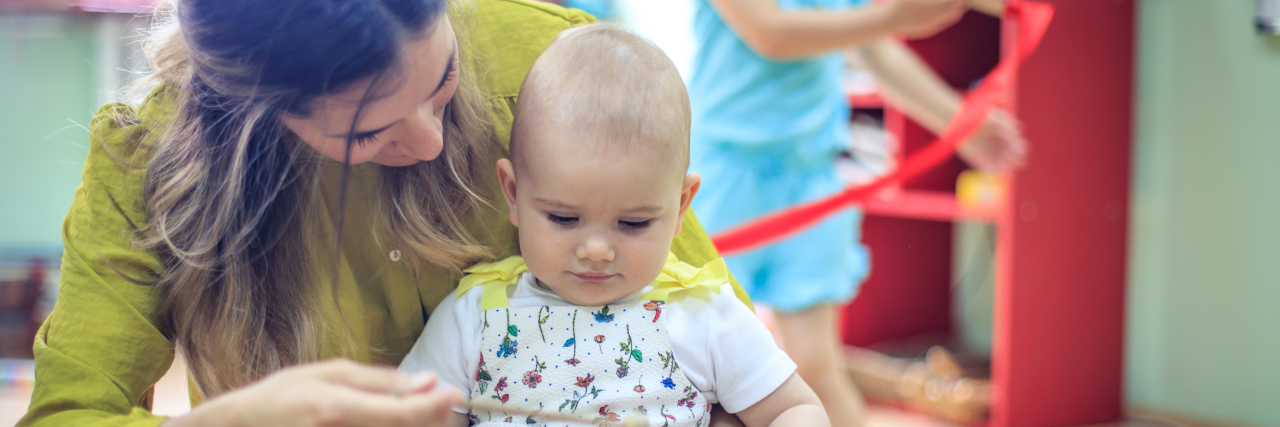 When Opinions About How I Parent My 'Work Kids' Become Overwhelming A woman sitting on the floor playing with an infant