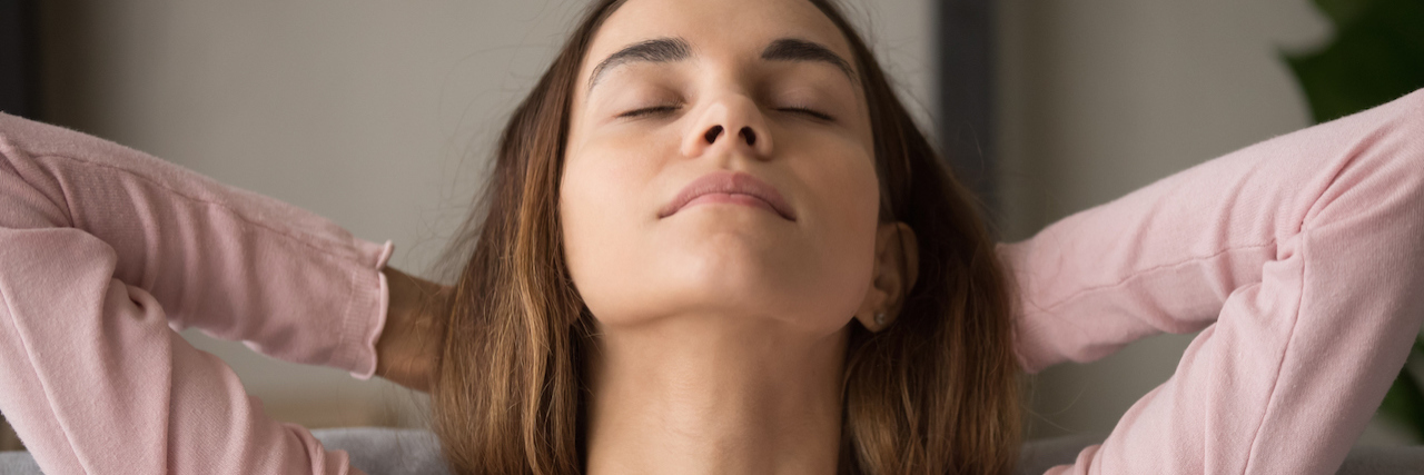 A Therapist Explains What It Means to 'Find Your Center' A woman looking up with her hands behind her hand