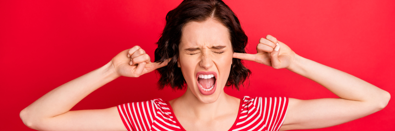 The Impacts of PCOS on Physical and Mental Health woman putting fingers into her ears, looking frustrated, wanting to scream