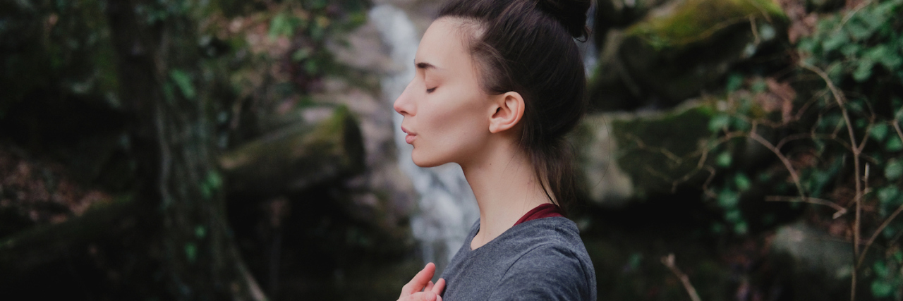 Tips for Practicing Yoga When You're Limited by Chronic Illness Young woman practicing breathing yoga pranayama outdoors