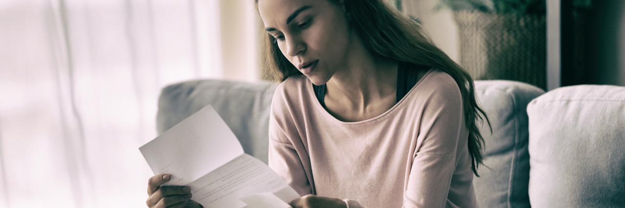 What 'Shielding' Is Like in the UK During the COVID-19 Pandemic Woman sitting on the couch reading a letter.
