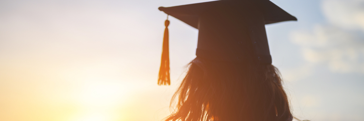 Woman wearing a graduation cap and looking at the sunset