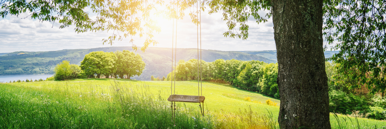 My Mixed Feelings About Mother’s Day as a Woman With No Children Old wooden vintage swing hanging from tree in meadow.