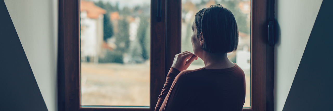 What COVID-19 and Postpartum Mood Disorders Have In Common A woman looking out a window