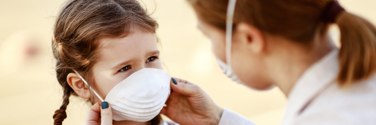 Dear Herd: Please Help Protect My Immunocompromised Child Mother putting medical mask on daughter