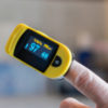 Close-up of hand with pulse oximeter attached to finger measuring blood oxygen and pulse rate