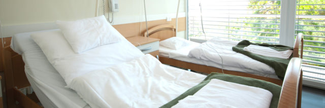 Two empty hospital beds by a window