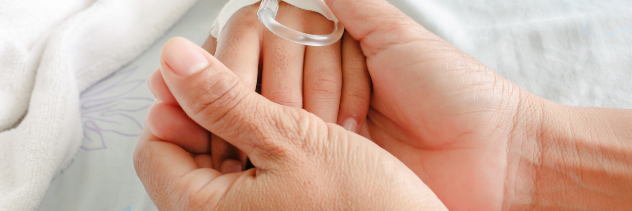 The Faith and Fear That Comes When Your Child Falls Gravely Ill a mom cradling her child's hand that has an IV tube in it