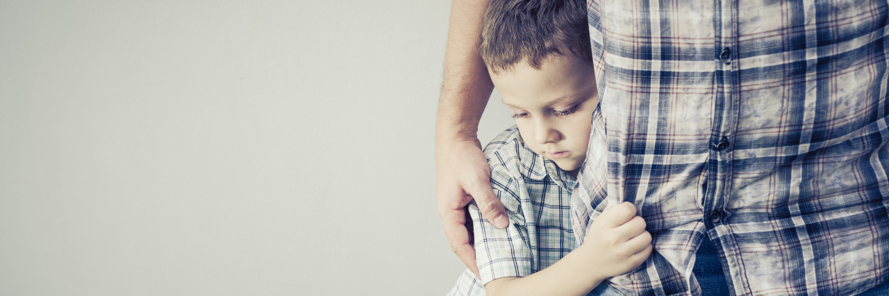 son hugging his dad's leg. sadness.