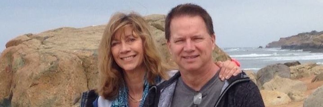 How a Leak in My Spinal Cord Convinced Me It Was 2007 a woman and her husband sit on a rock by the shore and smile