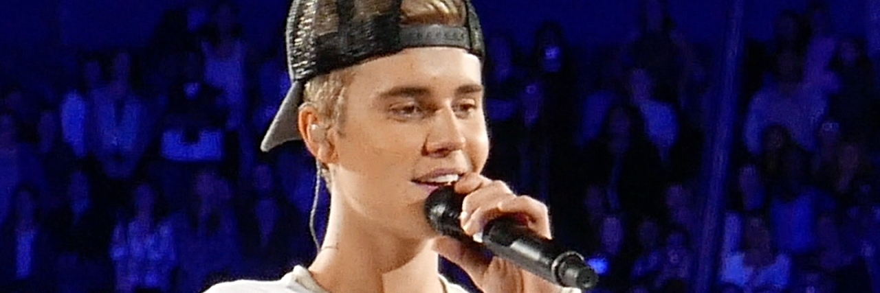 Justin Bieber in a white outfit performs onstage at a concert