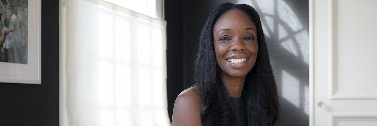 Nadine Burke Harris, a black woman with long hair, sitting at a desk