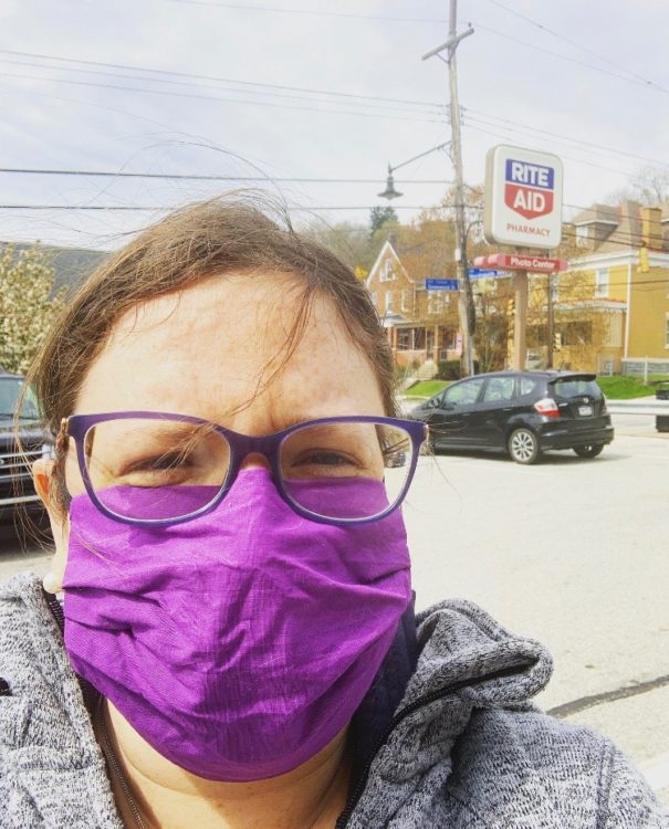 A photo of a white woman with brown hair and glasses wearing a purple standing in front of Rite Aid