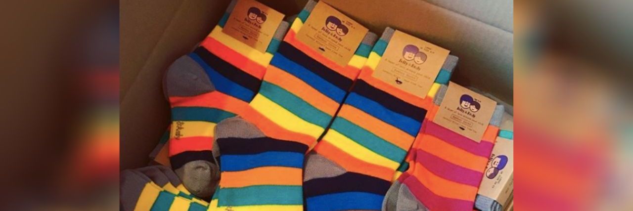 Polly and Andy rainbow sensory friendly socks piled in a cardboard box