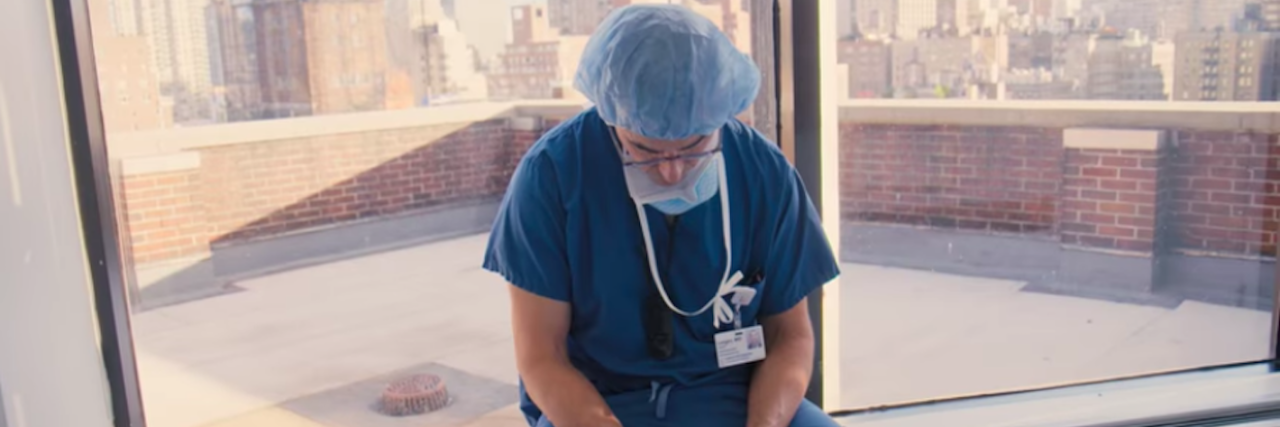 New Netflix Docuseries 'Lenox Hill' Follows Doctors Inside Hospital Lenox Hill Hospital doctor in scrubs and hair net sitting on the ledge of a window with hands folded, looking at the floor
