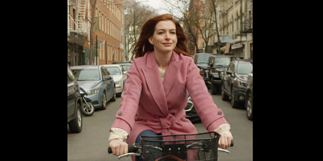 The First Time I Saw Myself On Screen as a Woman With Bipolar Disorder Anne Hathaway riding a bike through New York in a pink jacket