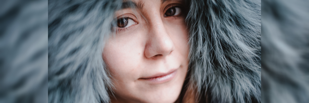 How to Recover After Being Stalked close up photo of woman looking into camera with sad eyes and wearing a fur hood