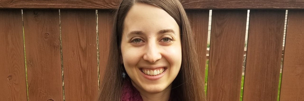 Remember Those With Chronic Illness After the COVID-19 Pandemic Beth standing outside by a fence.