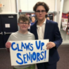 Alex holding sign reading "Claws up seniors!"