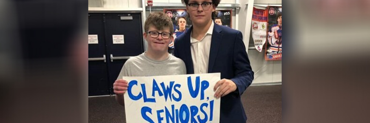 Alex holding sign reading "Claws up seniors!"