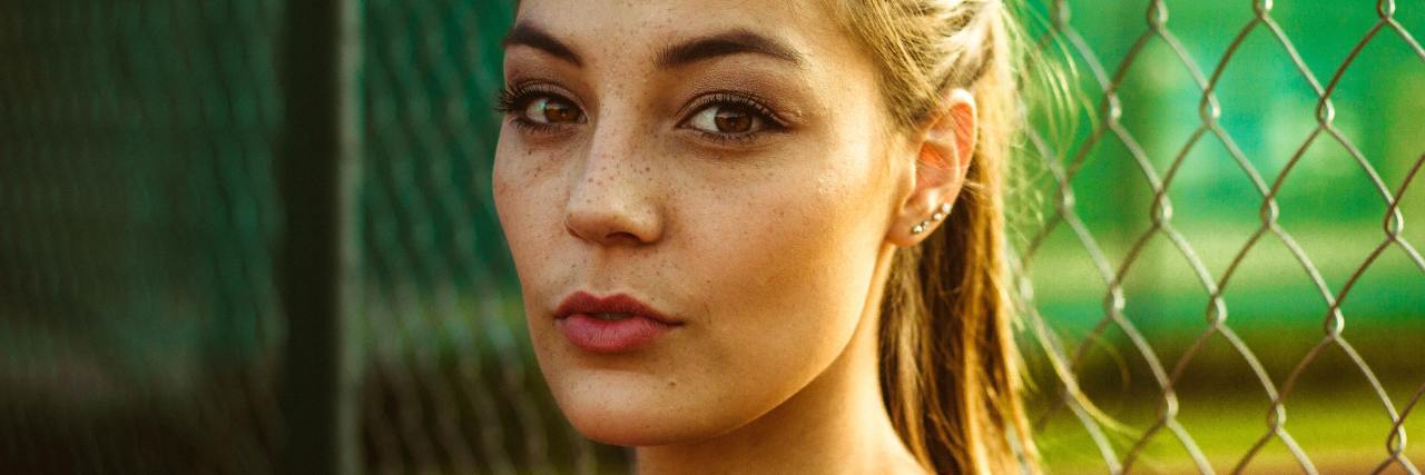 A Woman With Hidden Anxiety and Depression Tells Her Story A woman outside next to a fence