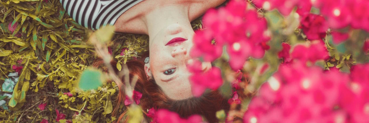 How Different Seasons Can Trigger Trauma Anniversaries Woman looking up with pink flowers in foreground