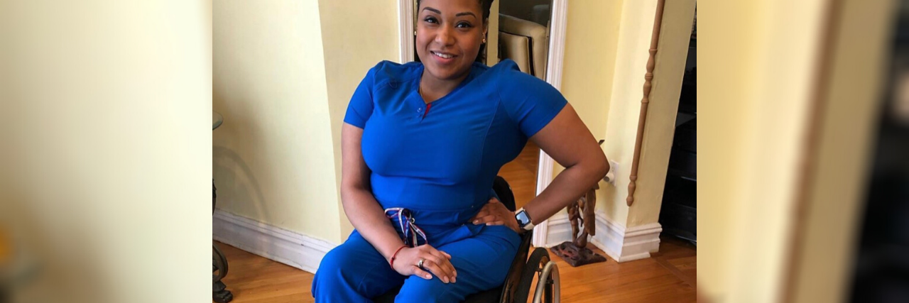 Andrea Dalzell in her blue nurse's uniform, sitting in her wheelchair.