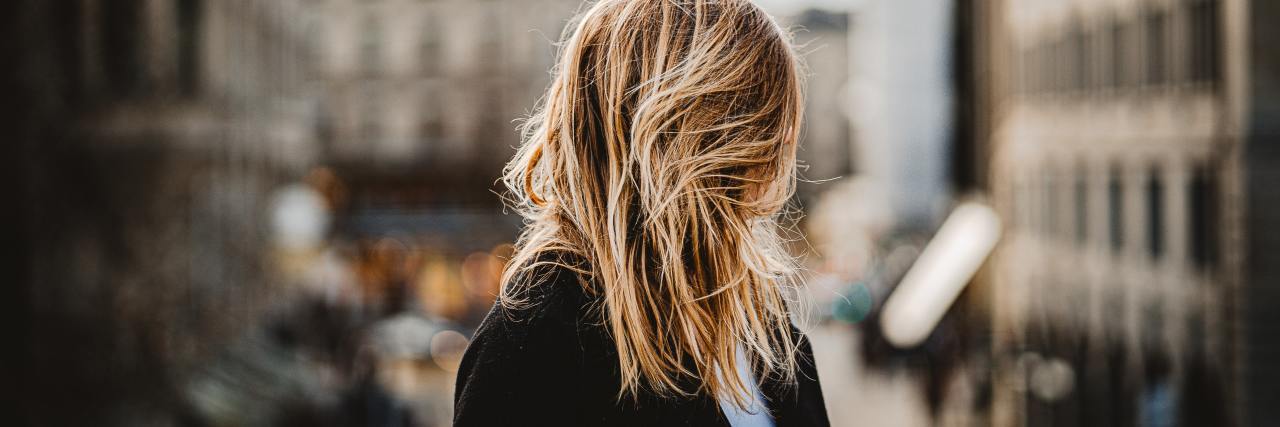 Struggling With COVID-19 and Change in Eating Disorder Recovery photo of woman with blurry city background and blonde hair covering her face