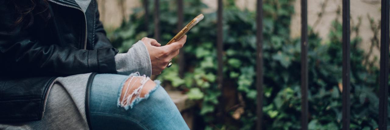 Why TikTok Might Be Dangerous in Eating Disorder Recovery close up photo of woman sitting with legs crossed and cellphone in her hand