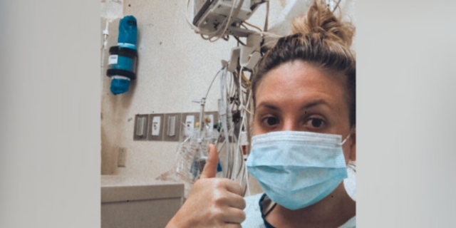 Contributor in hospital wearing a mask and giving thumbs up