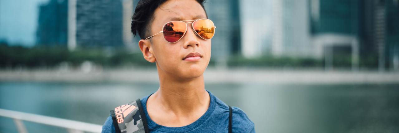 How a Breakup Actually Helped My Mental Health photo of young man wearing sunglasses with skyscraper buildings and water behind him