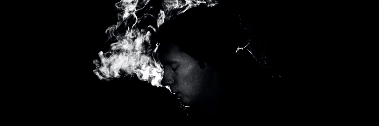 A Break-Up Letter to My Addiction black and white photo of man in darkness with eyes closed and backlit smoke