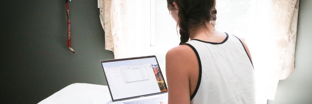 A Therapist's Advice for Getting the Most Out of Virtual Therapy photo of woman sitting on bed with laptop and camera