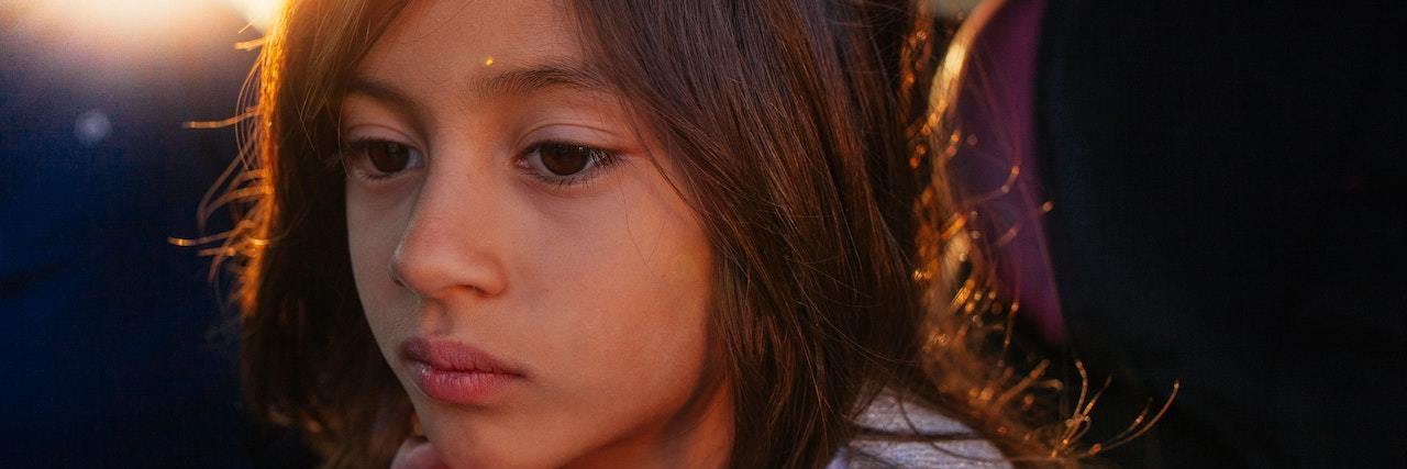 Kids With Chronic Illness More Likely to Struggle With Mental Health Young girl with medium-length brown hair sitting in a car with her hand near her chin