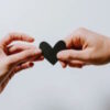A hand holding onto a black heart