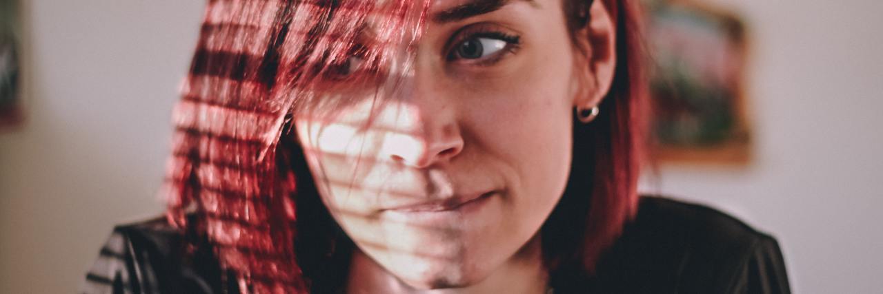 photo of woman with red hair siting in sunlight and biting her lip while looking away