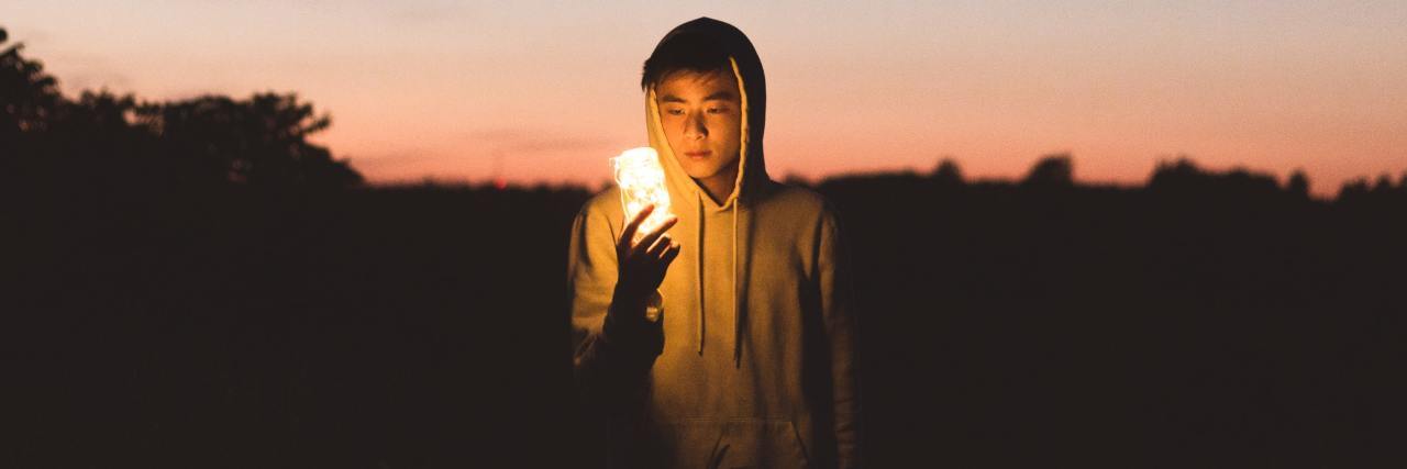 What to Do If Your Depression and Anxiety Are Worse at Night photo of man standing in darkness at sunset, holding lights in his hand and looking into them