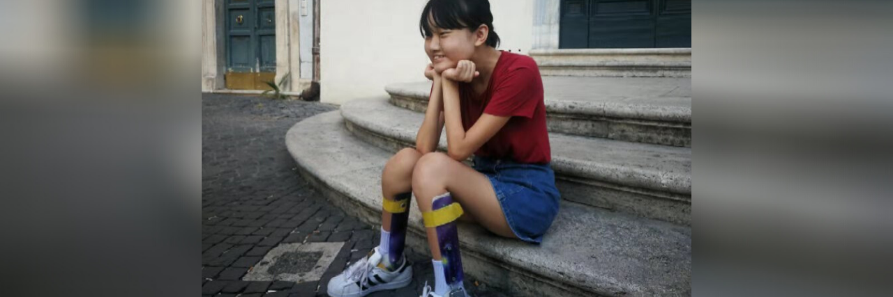 Melissa wearing her leg braces, sitting on steps.