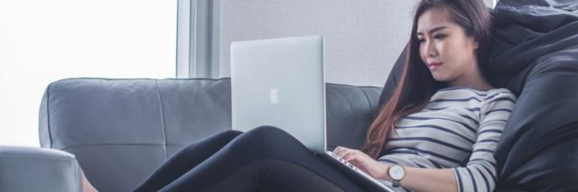 photo of woman lying on couch with laptop working from home