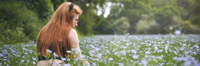 photo of woman sitting in field with white flowers