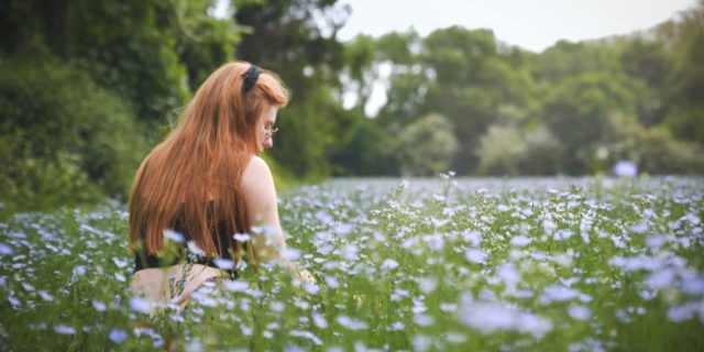 photo of woman sitting in field with white flowers