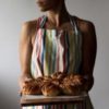 a woman in an apron holding pastries