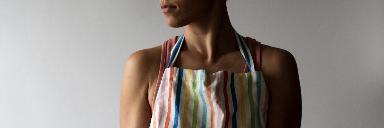 Fibromyalgia Makes Me Feel Guilty Because I Can't Be a 'Perfect' Wife a woman in an apron holding pastries