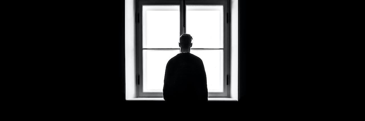 Study: Believing Biological Cause of Depression Leads to Less Stigma Man silhouetted against a window in black and white